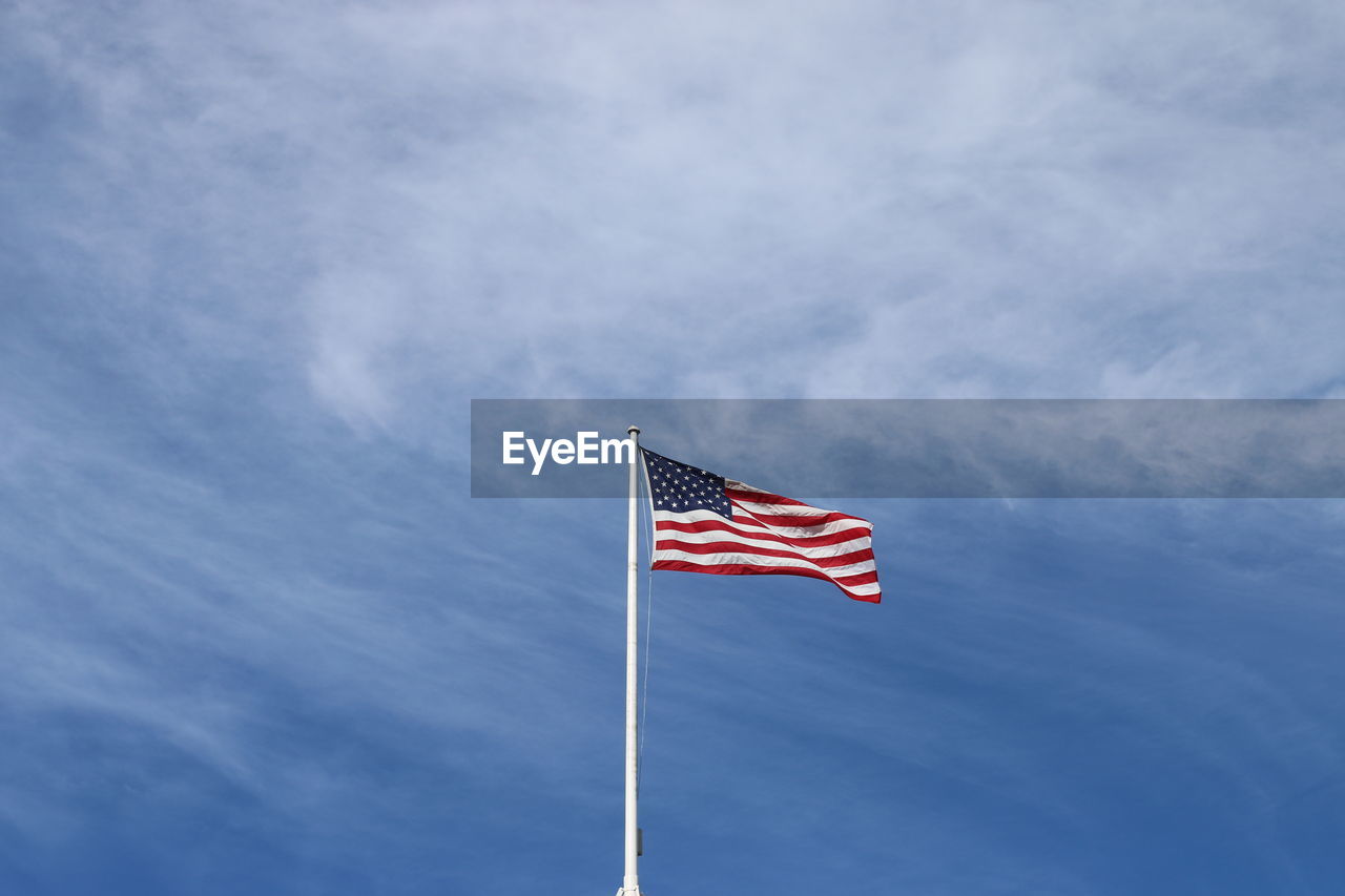 Low angle view of flag against cloudy sky