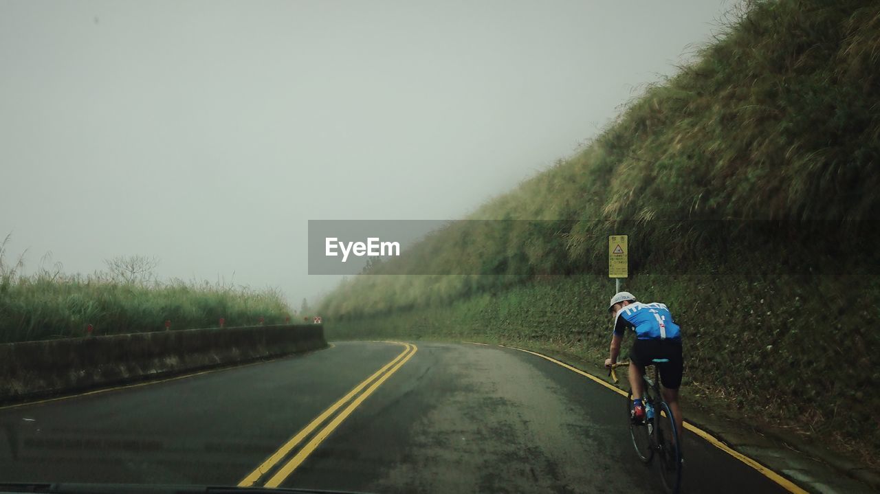 Rear view of person riding bicycle on road