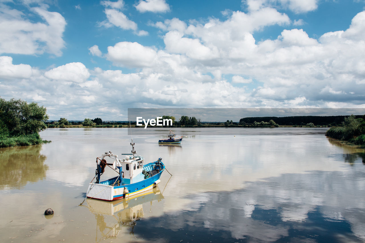 Fishing boat in lake against sky