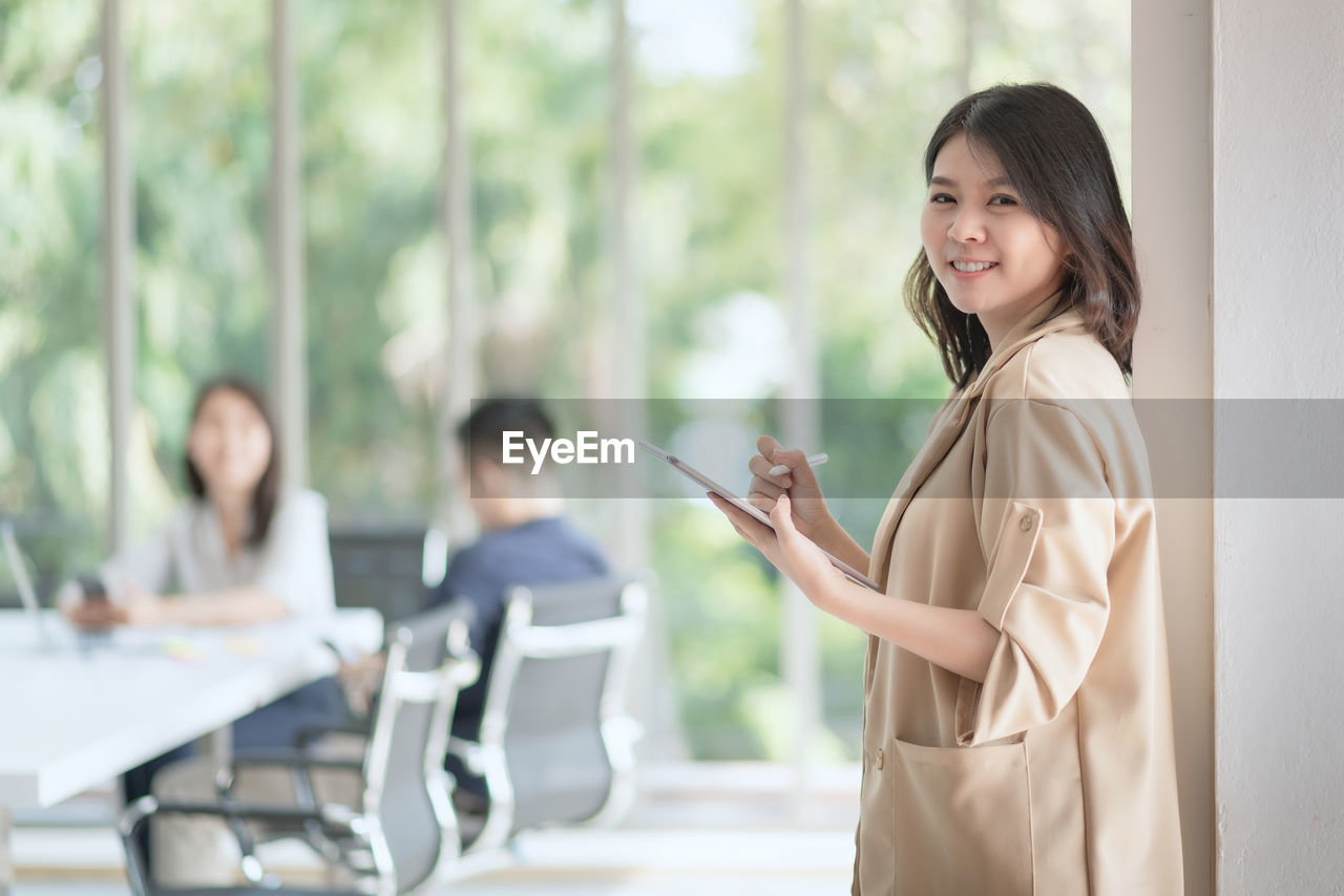 Portrait of a smiling young woman using tablet for working