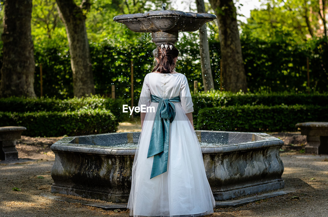 Rear view of girl standing in front of fountain in park