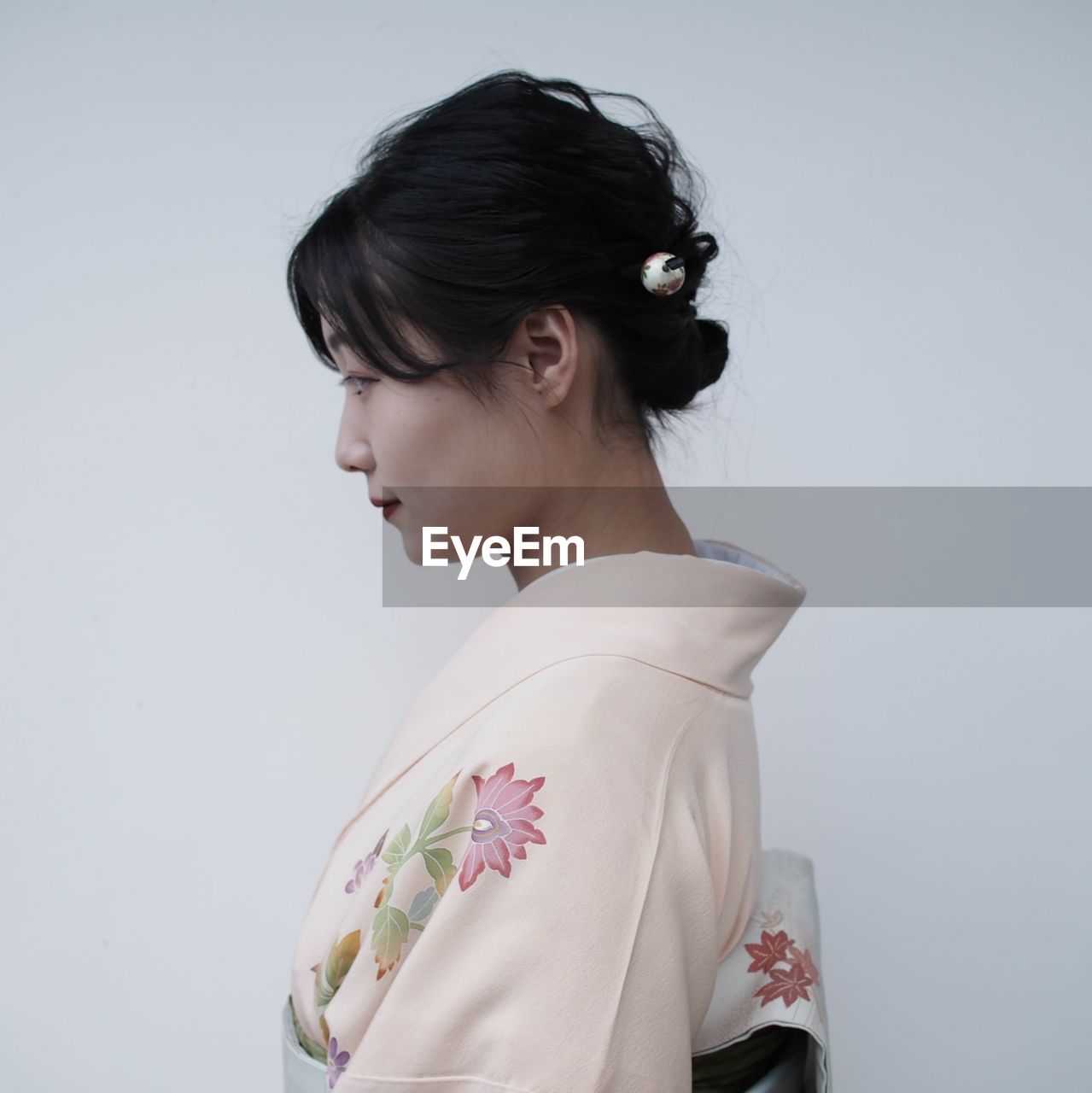 PORTRAIT OF YOUNG WOMAN AGAINST GRAY BACKGROUND