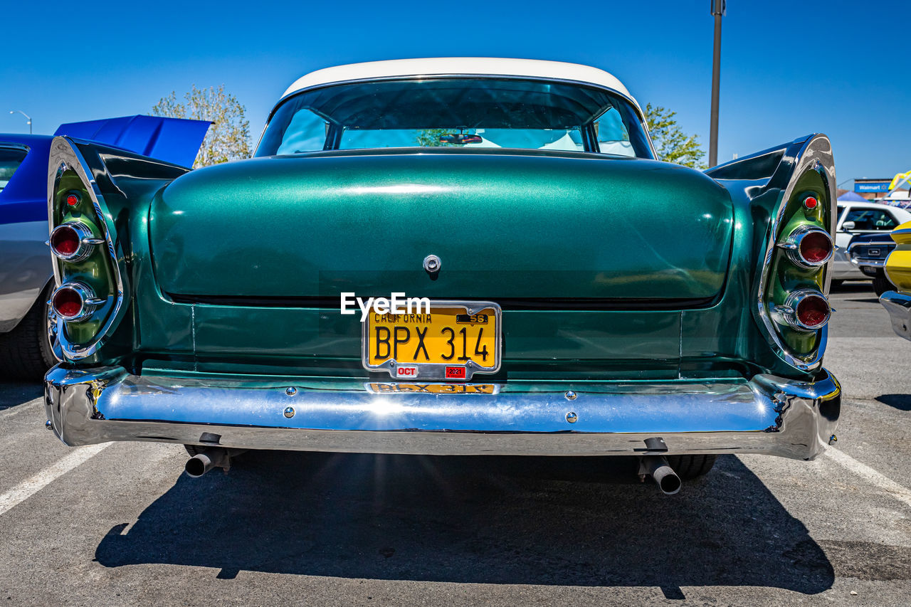 car, vehicle, land vehicle, mode of transportation, transportation, motor vehicle, blue, antique car, luxury vehicle, vintage car, retro styled, automotive exterior, sky, automobile, text, sunlight, day, sunny, clear sky, road, nature, travel, outdoors, compact car, city, wheel