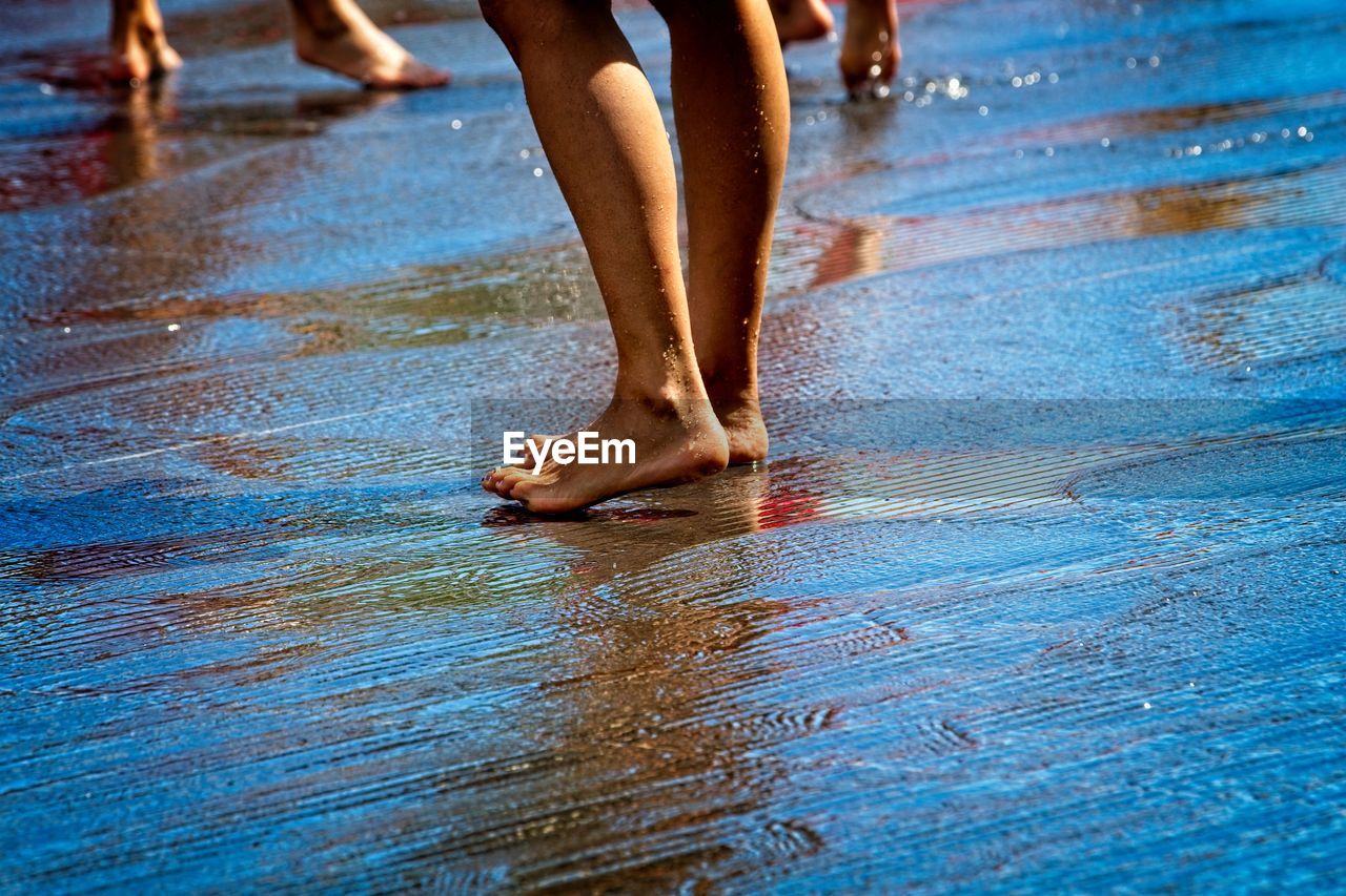 Low section of people standing on land with water