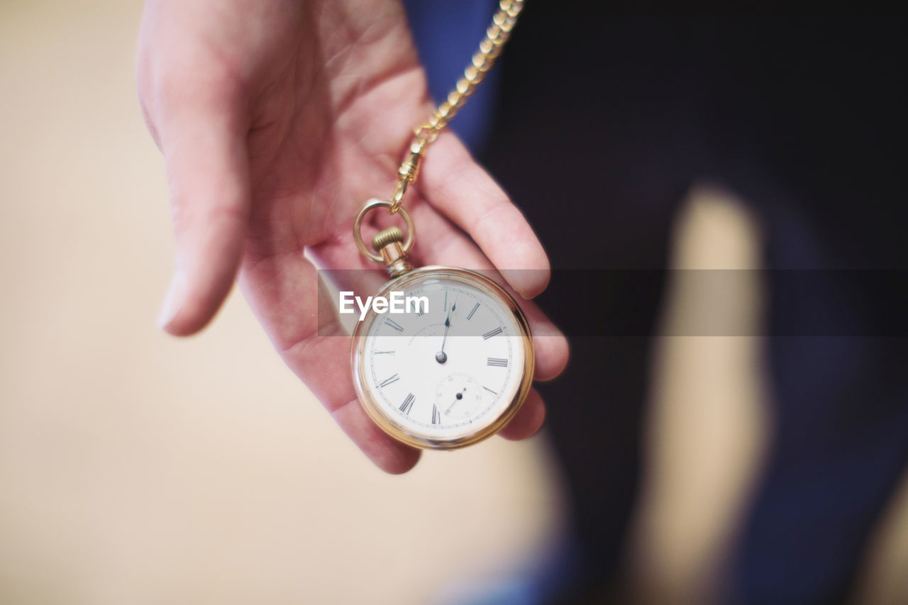 Close-up high angle view of human hand holding pocket watch outdoors