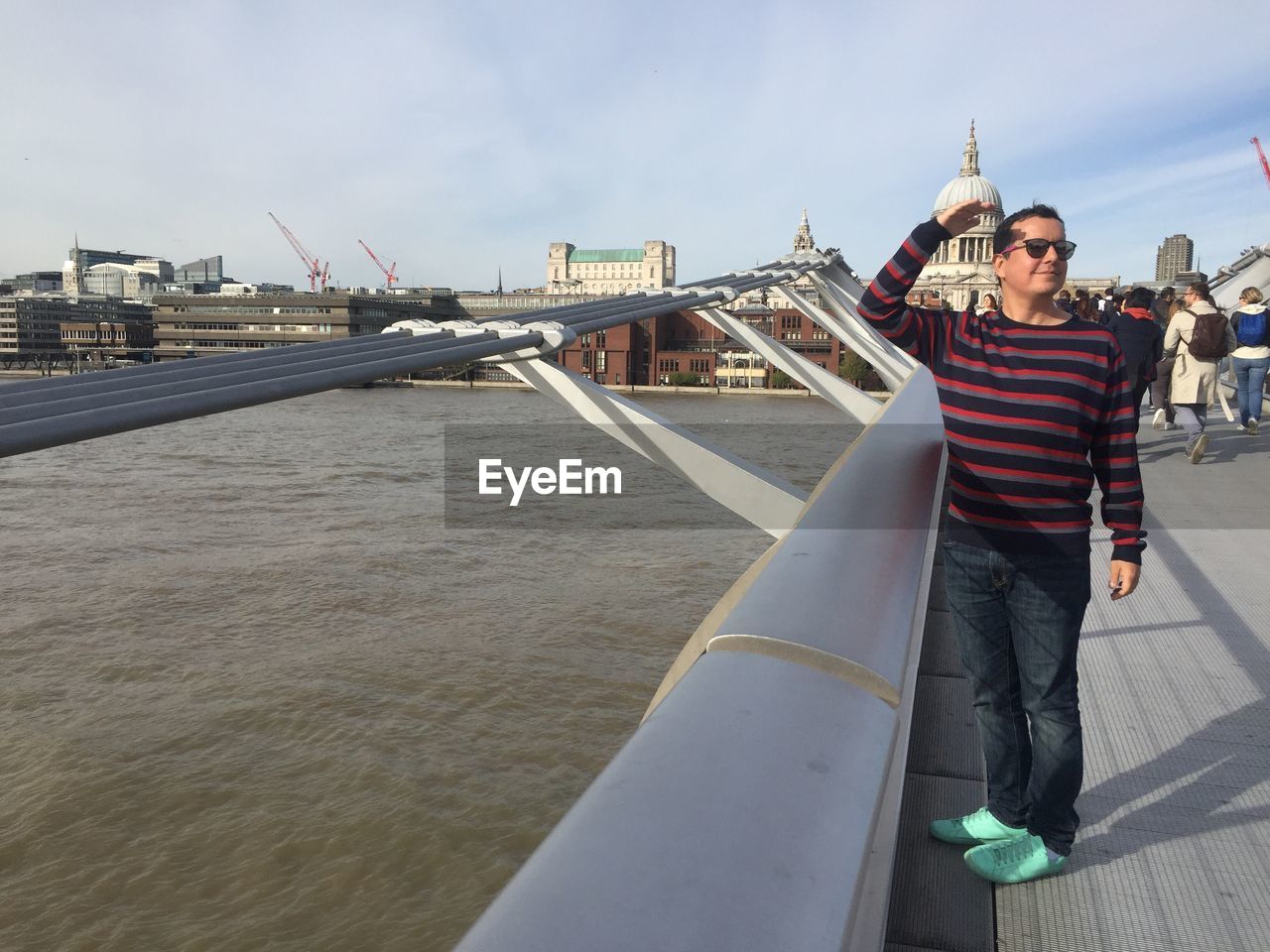 Man standing by railing over river against sky