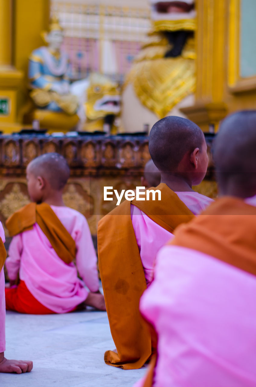 Rear view of monks sitting in temple