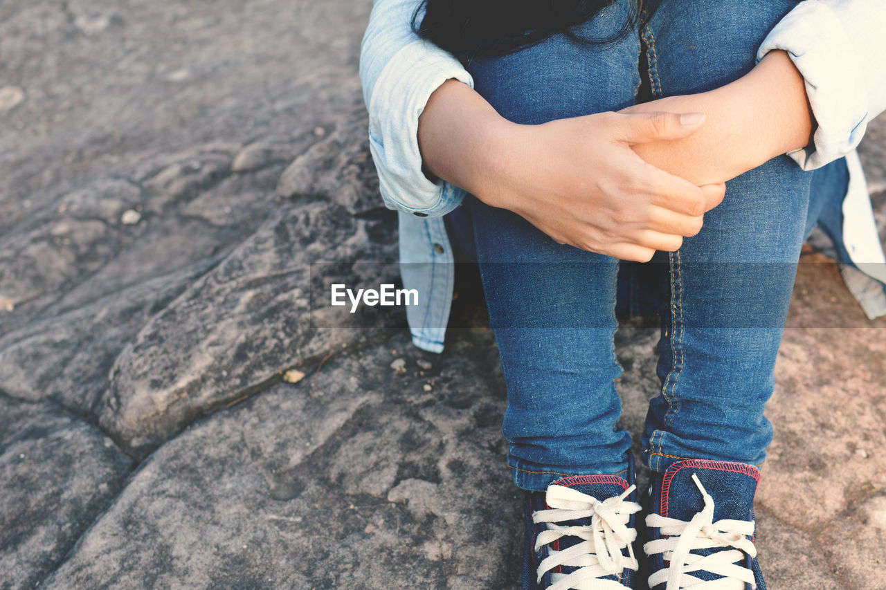 Midsection of woman sitting on rock