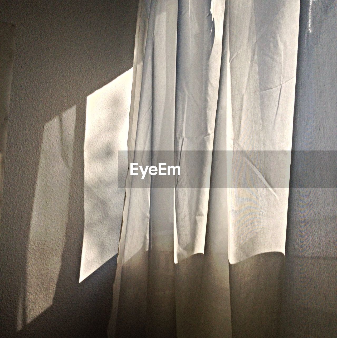 Cropped image of curtain with shadow on wall