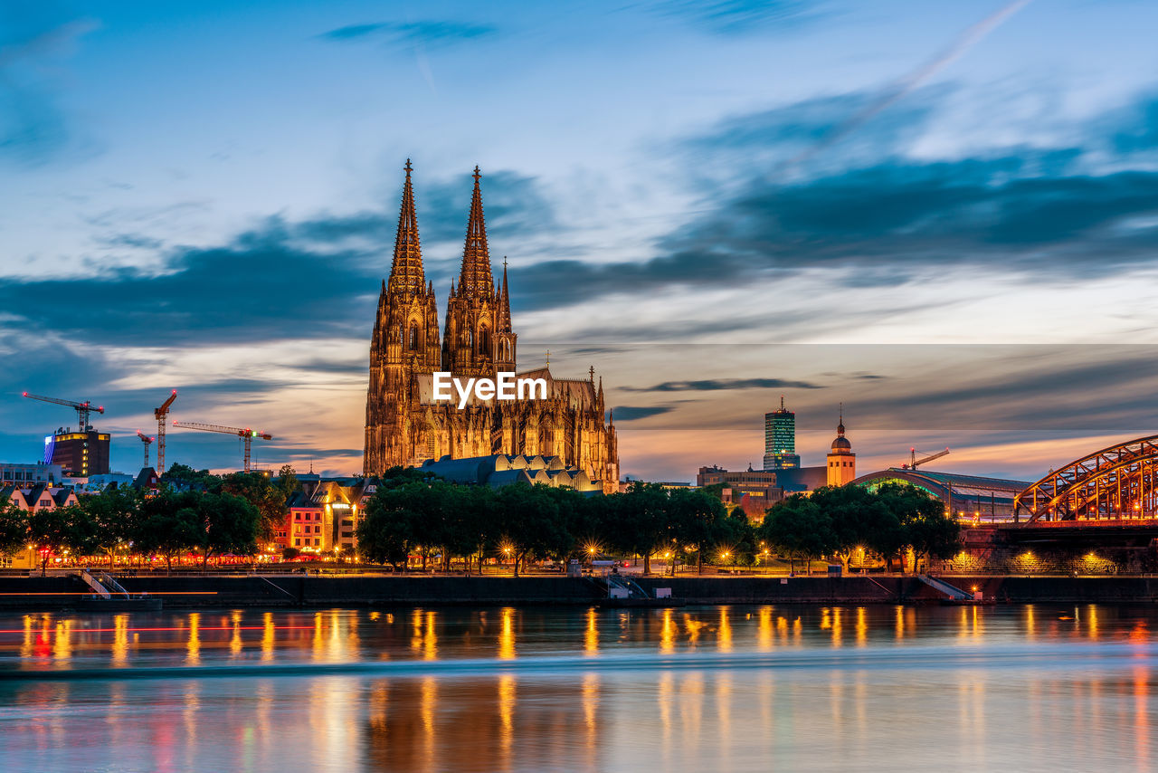 Panoramic view of cologne cathedral with hohenzollern bridge at nightfall, germany.