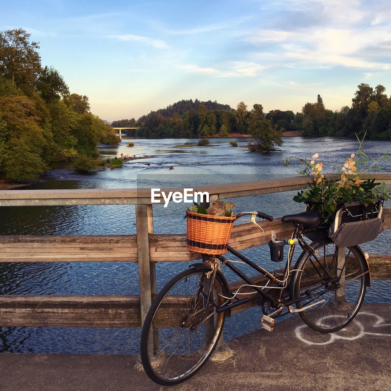 Bicycle by lake against sky during sunset