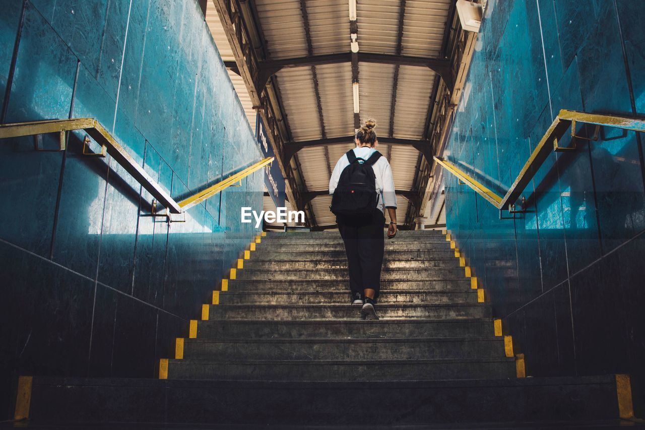 Rear view of woman walking on stairs at railway station