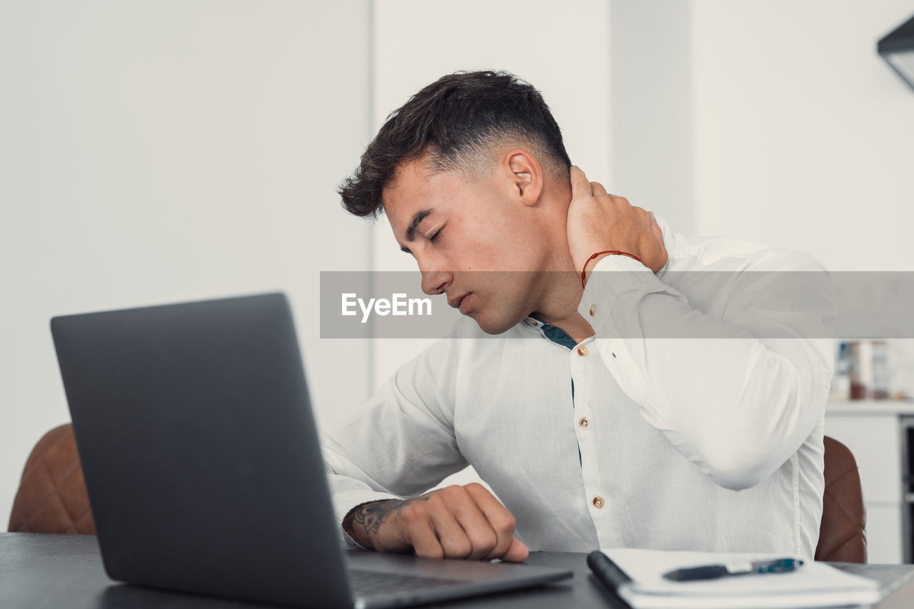 side view of young man using laptop while sitting on table