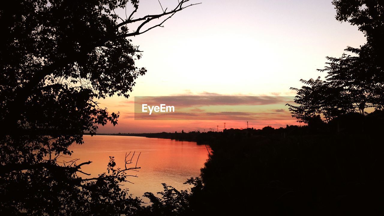 SCENIC VIEW OF LAKE AGAINST SKY AT SUNSET