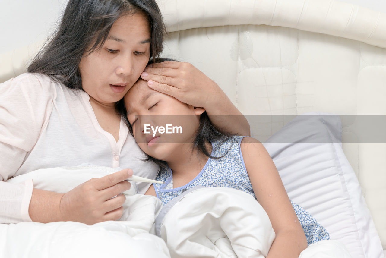 Mother checking temperature of her sick daughter, worry and health care concept