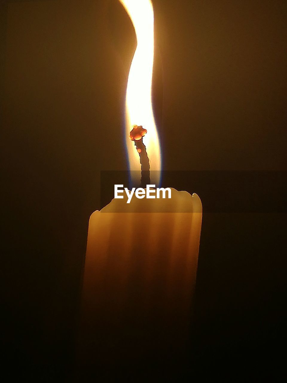 CLOSE-UP OF HAND HOLDING ILLUMINATED CANDLE