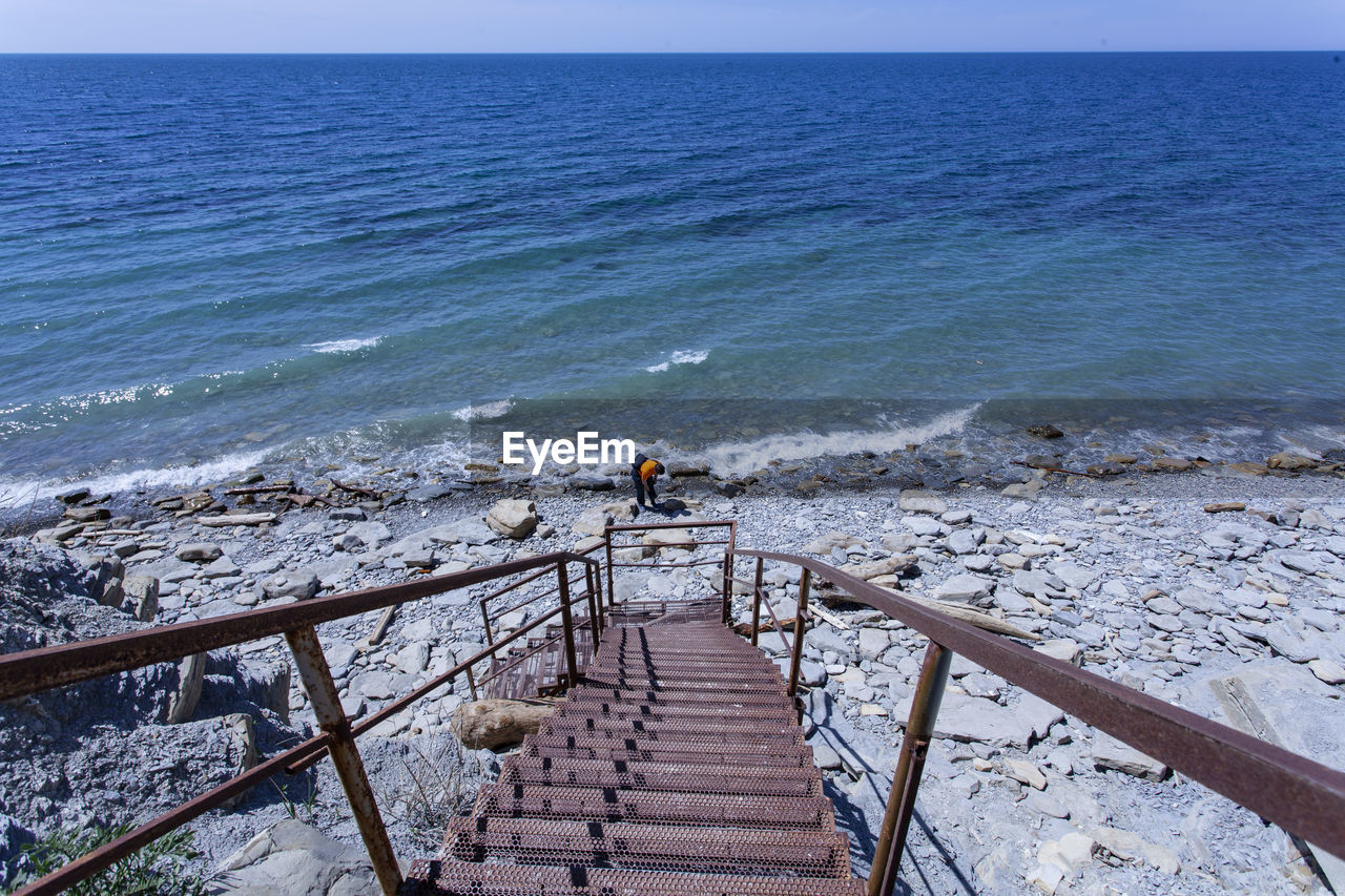 High angle view of man standing at beach during sunny day