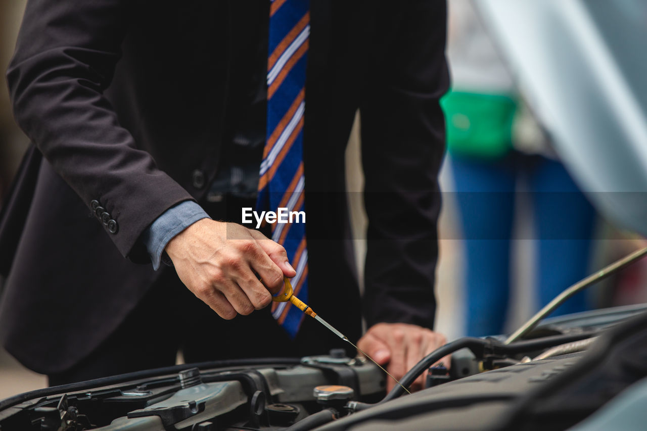 Midsection of businessman repairing car
