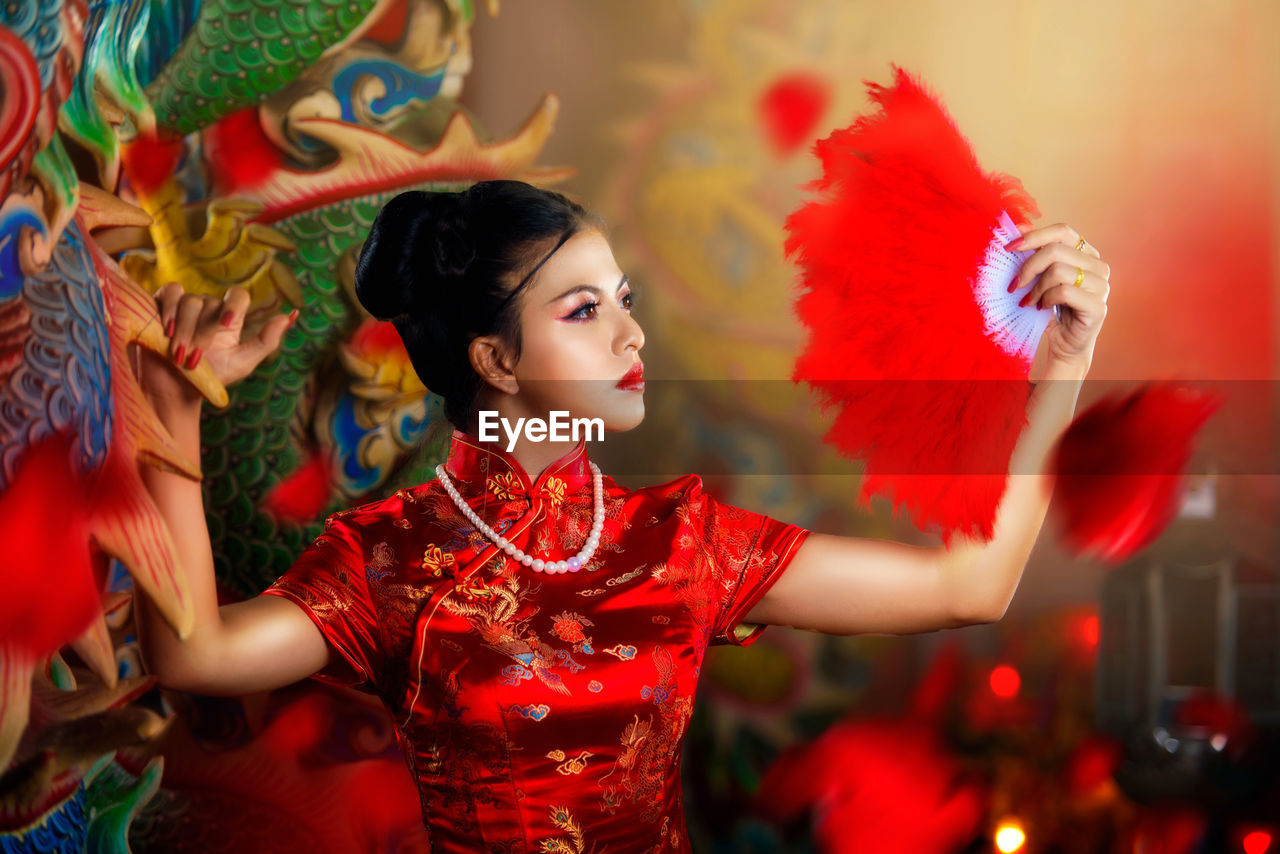 Beautiful young woman with hand fan looking away