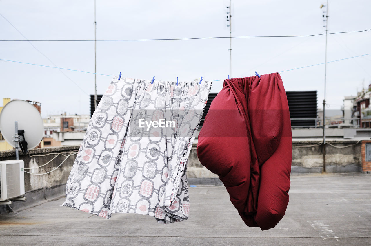 Clothes drying on clothesline at building terrace against sky