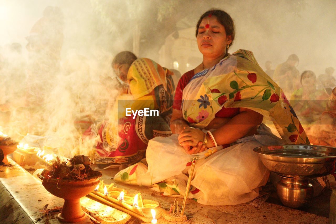 Doing prayer at barodi lokhnath brahmachari ashram infront of burning candle and diya- oil lamp