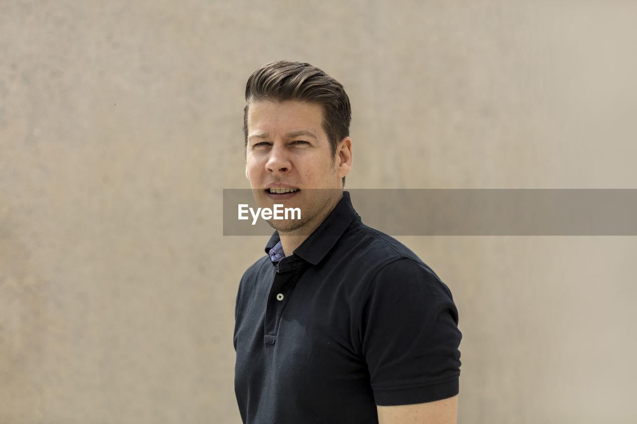 Portrait of young man standing against wall