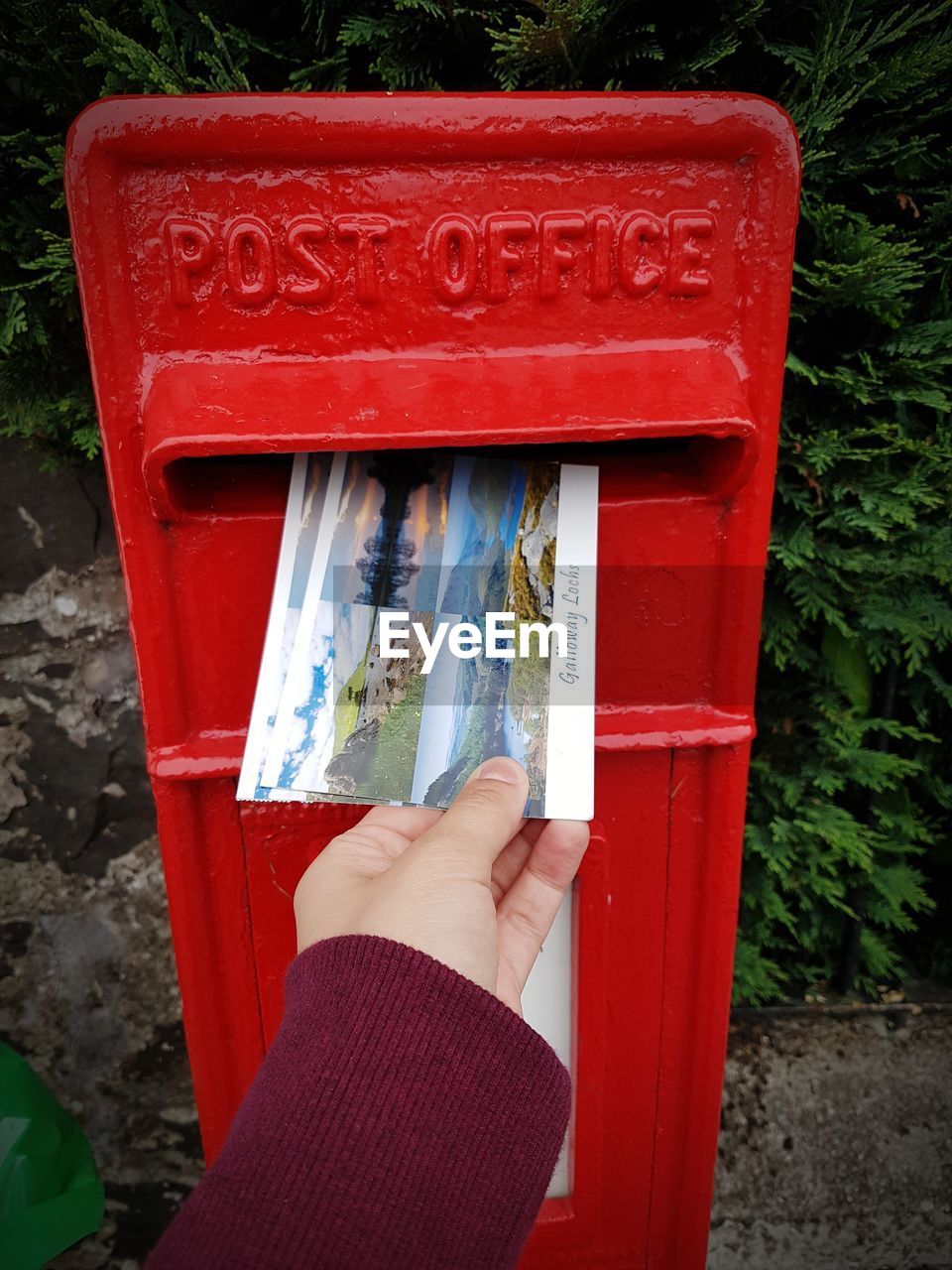 MIDSECTION OF PERSON HOLDING RED MAILBOX