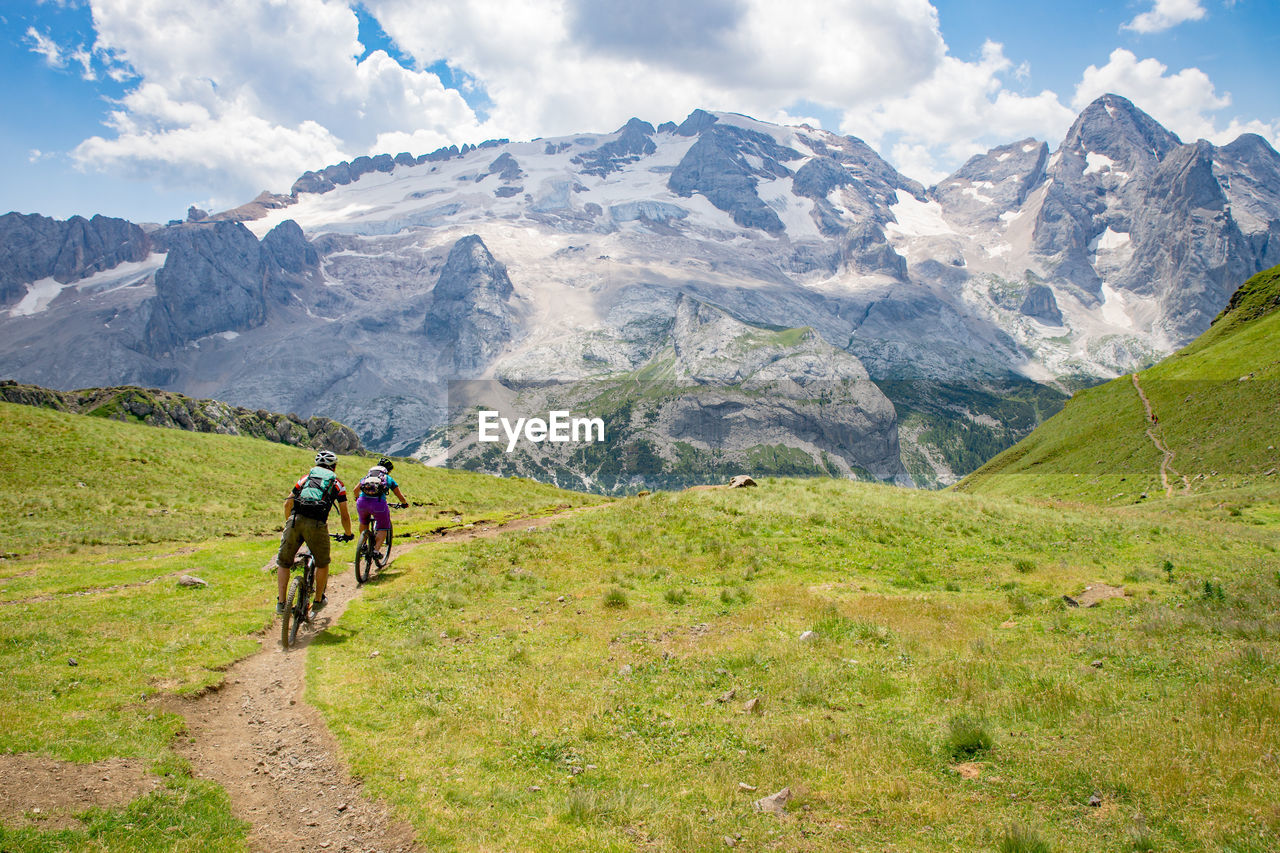 Man and woman riding their mountain bikes on footpath in the scenic dolomites, italy