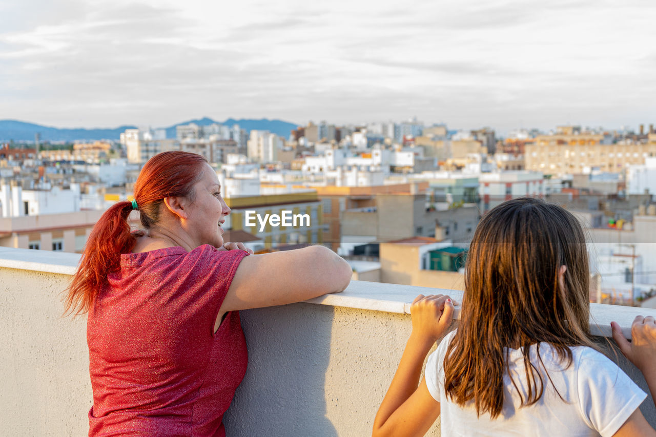 Rear view of woman in city against sky