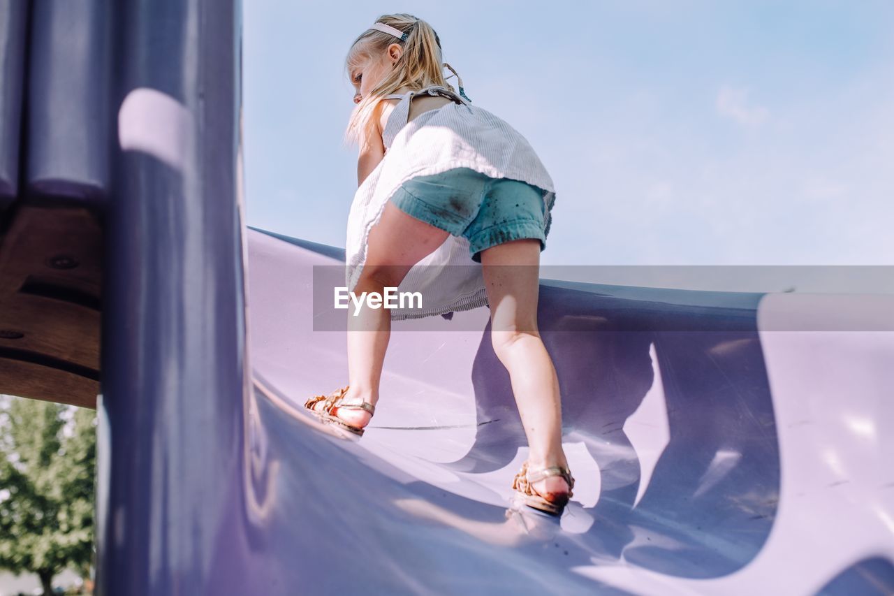 Full length of girl playing on slide against sky
