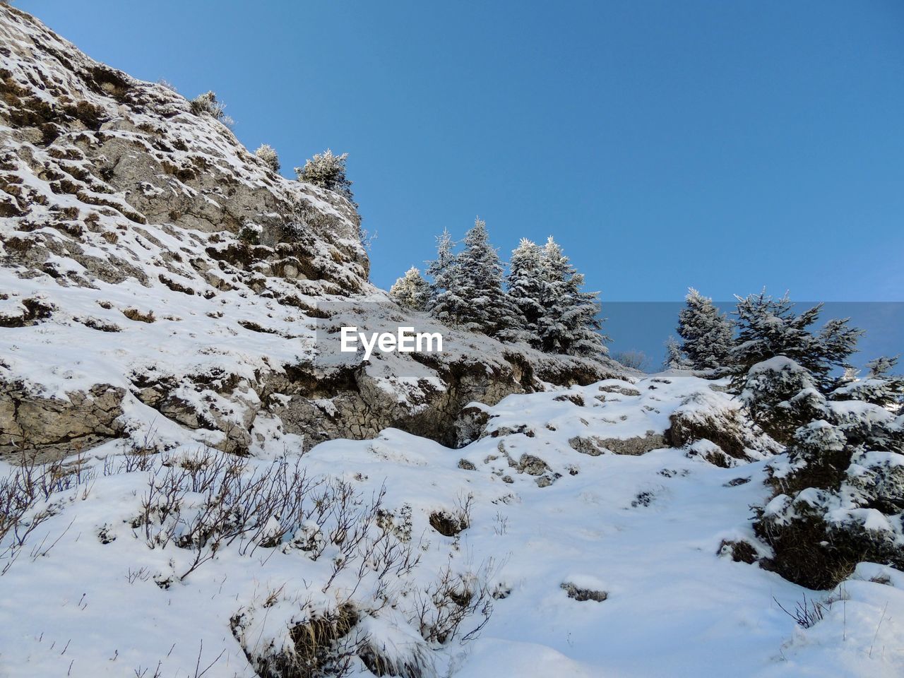 Low angle view of snowcapped mountain against blue sky