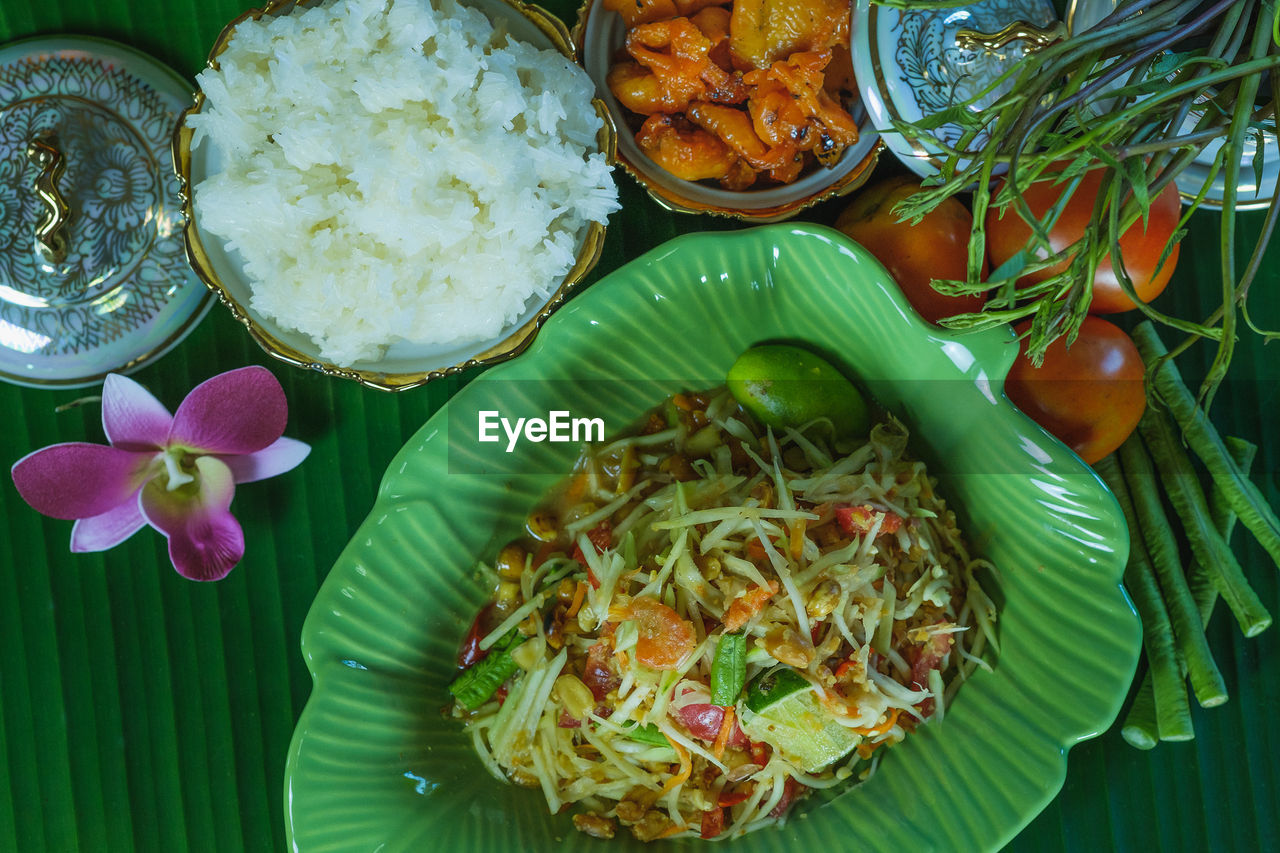 High angle view of papaya salad or som tam and sticky rice and grilled chicken.