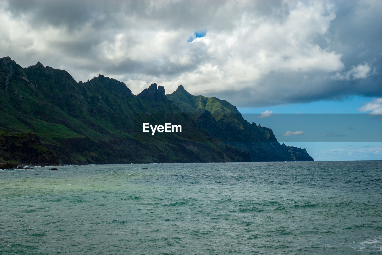 Scenic view of sea and mountains against sky