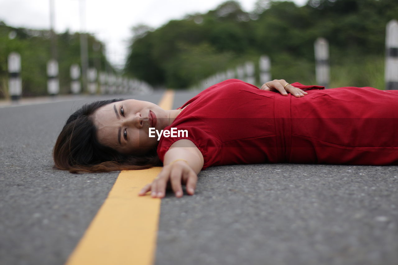 Rear view of woman lying on road