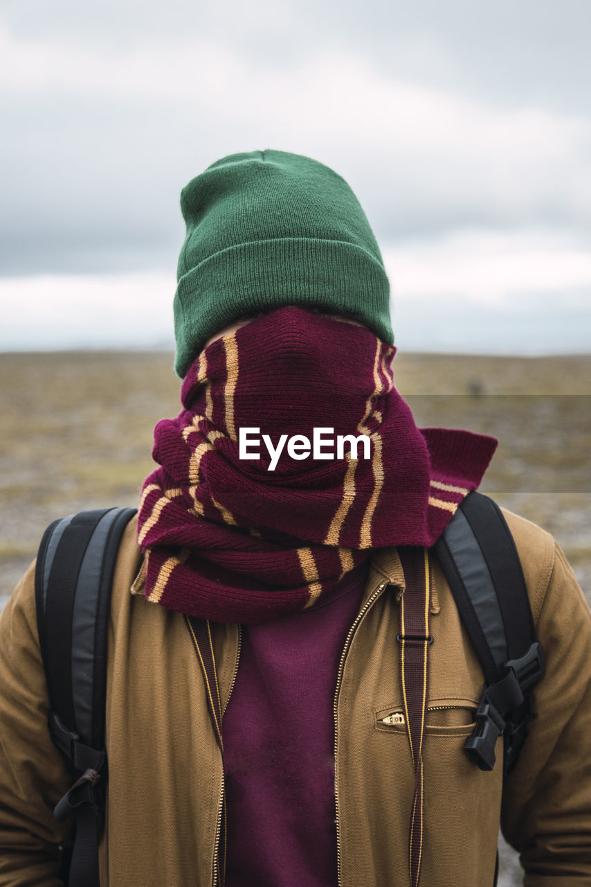 Young man with woolly hat and scarf, wrapped around face