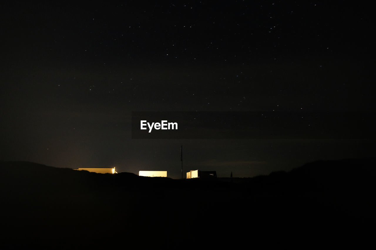 Silhouette buildings against sky at night illuminated