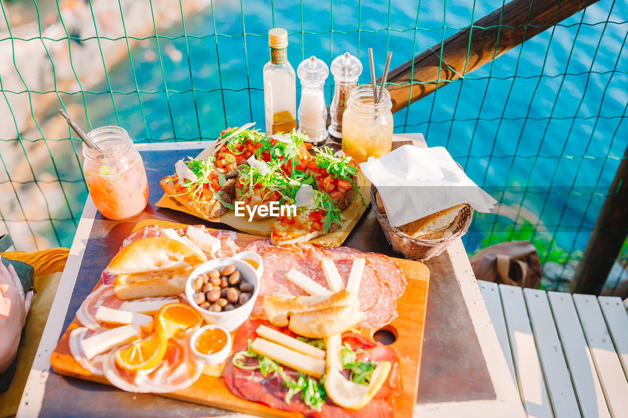 HIGH ANGLE VIEW OF FOOD SERVED ON TABLE AT SWIMMING POOL