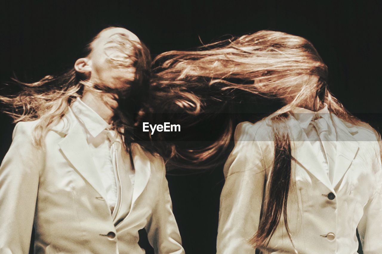 Multiple image of woman tossing hair against black background