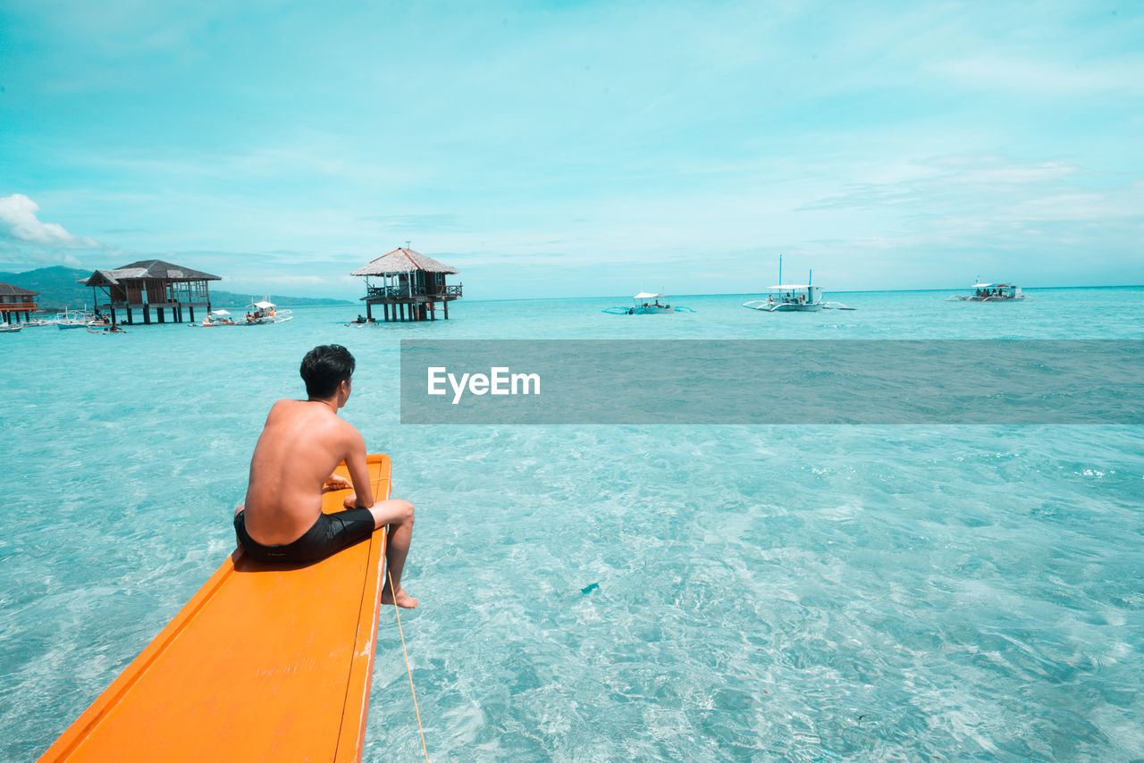 Rear view of man sitting in boat on sea