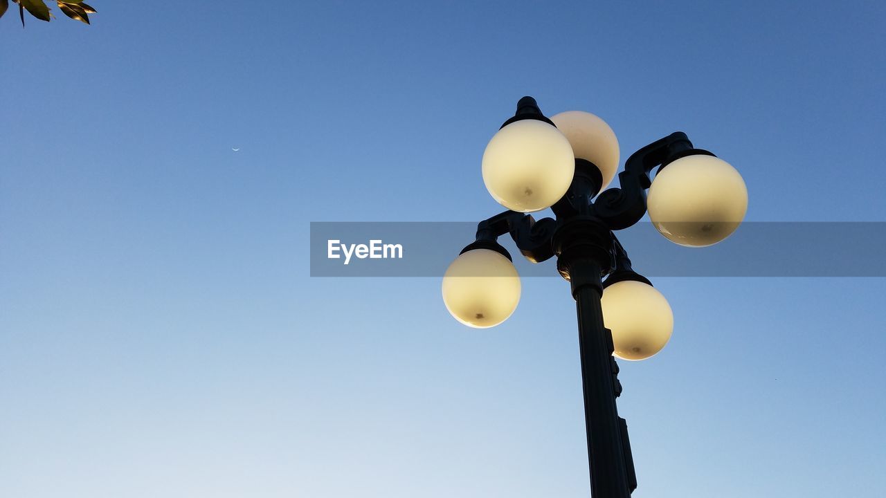 LOW ANGLE VIEW OF ILLUMINATED LAMP AGAINST BLUE SKY
