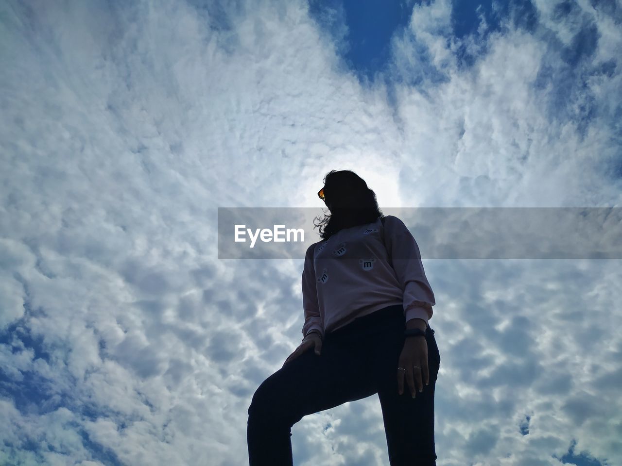 Low angle view of teenage girl standing against sky