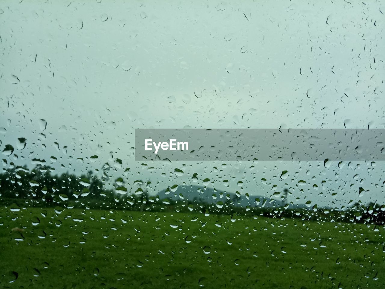 CLOSE-UP OF WATERDROPS ON GLASS AGAINST SKY