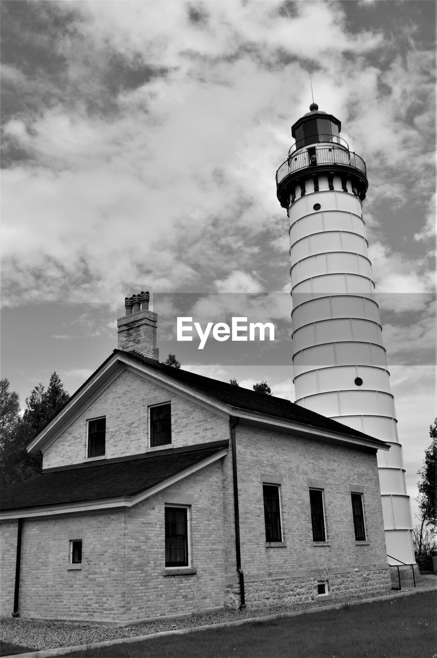 Low angle view of lighthouse by building against sky