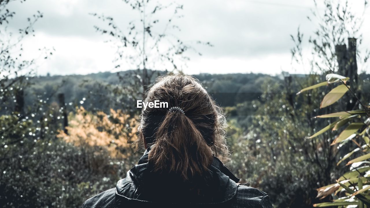 Rear view of woman looking at forest against sky