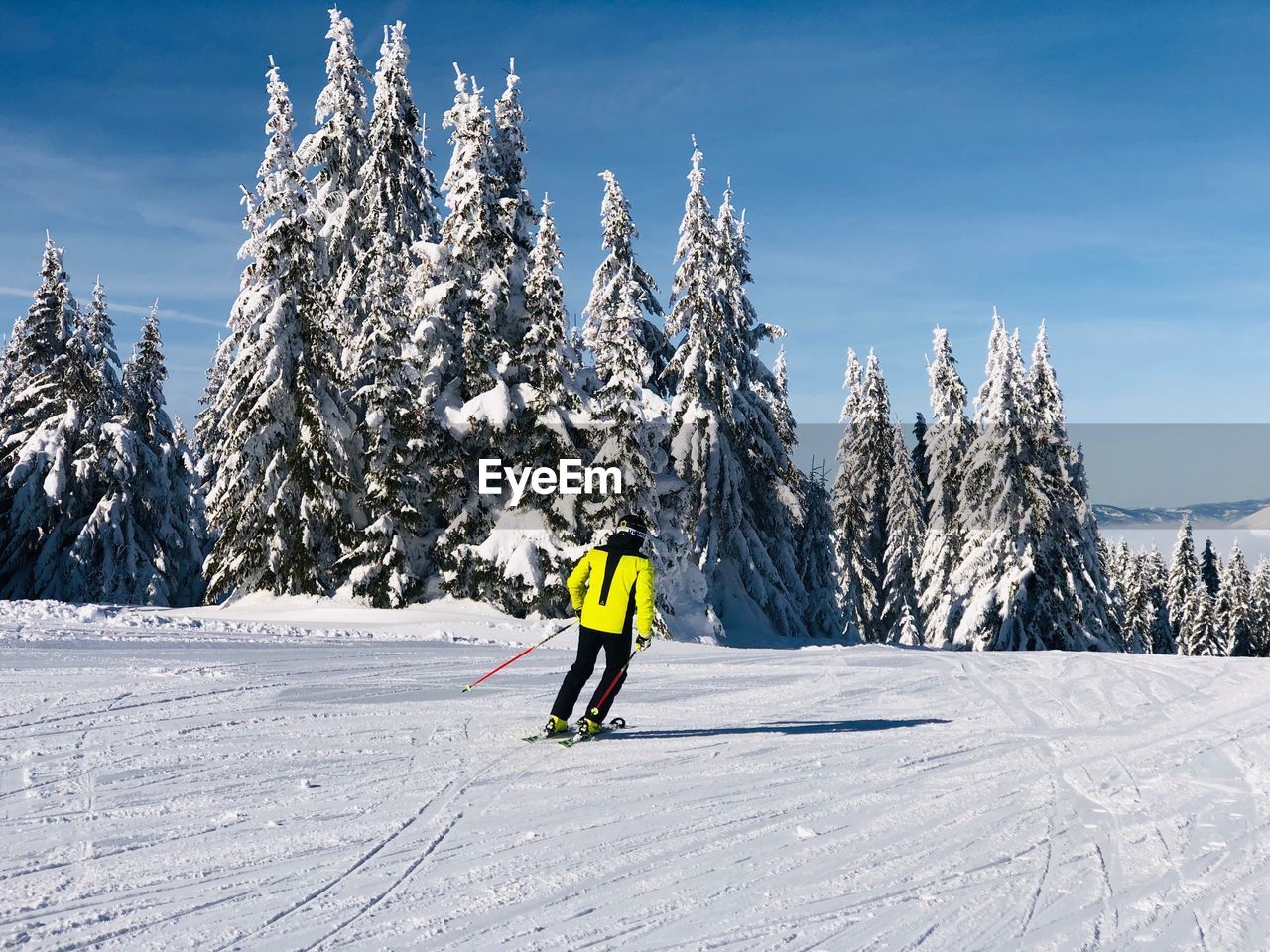 Rear view of man skiing on snow covered mountain against sky