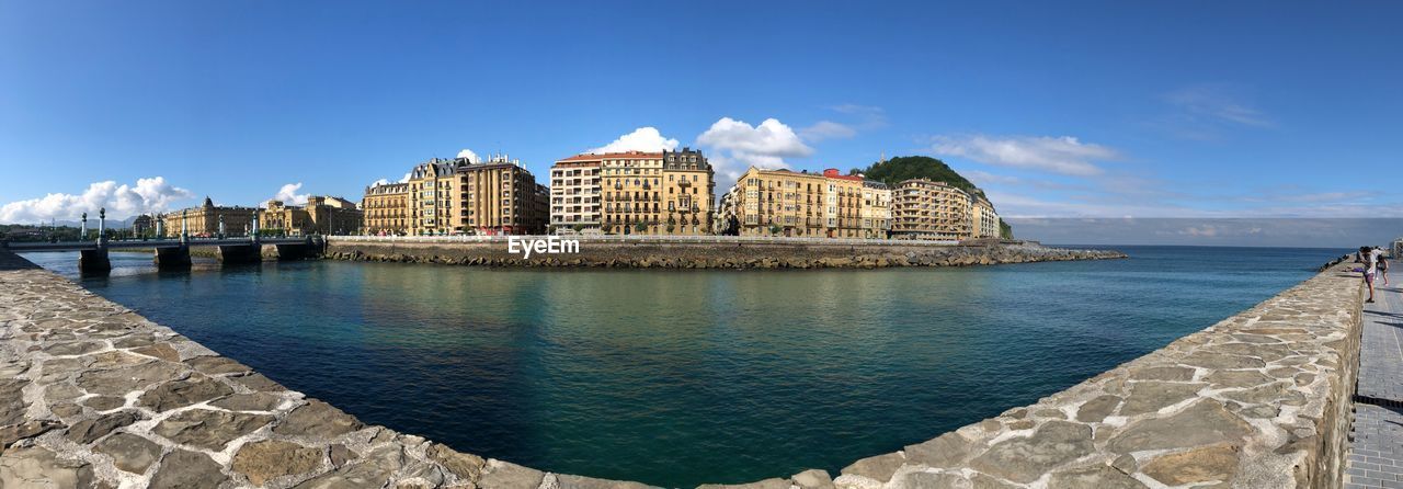 Buildings by sea against sky in city