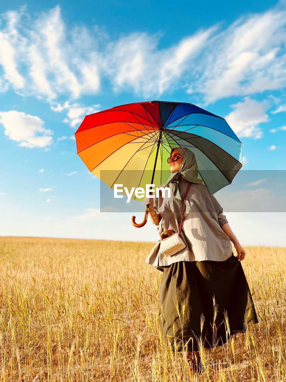 Rear view of woman with umbrella on field against sky