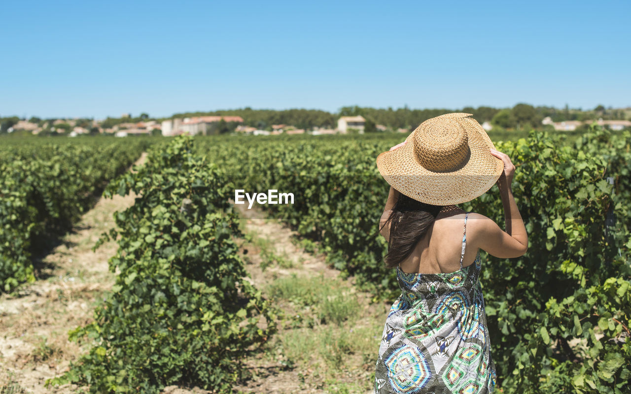 Rear view of woman standing at vineyard