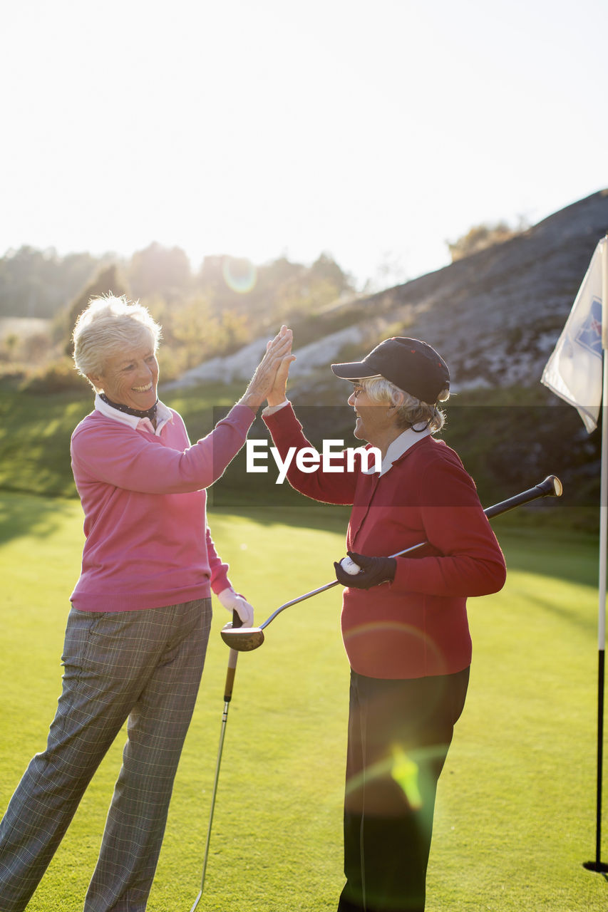 Happy senior female golfers giving high-five on golf course