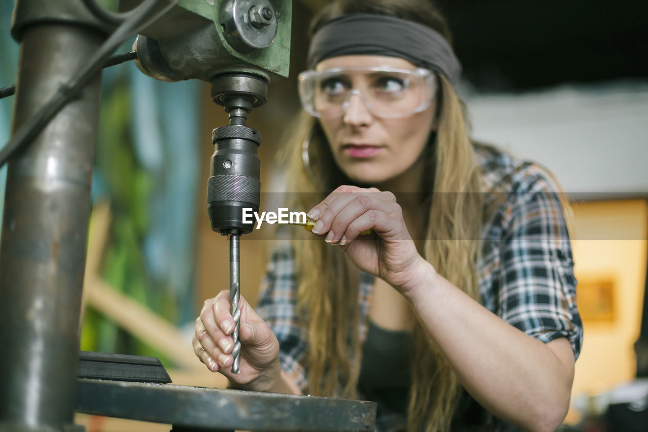 Woman with drill machine working in workshop